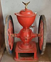 Front view of full coffee mill grinder showing cast iron body, flywheels and eagle finial