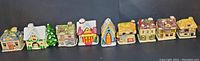 Front view of all 9 ceramic tealight Christmas village houses displayed linearly