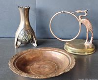 Wide angle view showing copper bowl, tall Art Nouveau style candle holder, and crane figurine with brass base and ring.