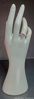 Photo of 925 silver ring with ribbed band and oval amethyst stone on display hand model.