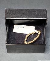 Ring inside an open black jewelry box on a black velvet cushion, displaying the 14KT label.