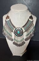 Front view of silver tone bib necklace with turquoise stones on display bust