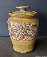 Front view of signed Sargent pottery jar with lid showing carved geometric designs and earthy glaze