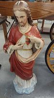 Full front view of large statue of Jesus showing Sacred Heart and robe details with paint chipping