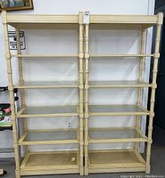 Front view of the two wooden shelving units side by side, showing six shelves each with glass inserts, in cream color.