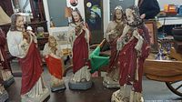 Photo showing all five religious statues arranged together on a table in a second-hand store setting.