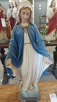 Full front view of the painted Mother Mary statue, showing front of robe and stance, with visible chips and wear marks.