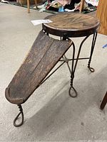 Overall view of antique shoe fitting bench showing wooden seat with metal trim and footrest.