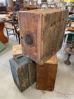 Three antique wooden crates stacked showing varying wood tones, marks, and branding