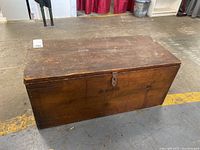Front and side view of antique wooden storage chest with aged patina and keyhole on lid.