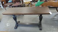 Full view of antique wooden console table showing rectangular top and carved pedestal legs.