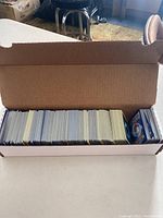 Cardboard box filled with a large quantity of Pokémon cards arranged upright in the box.