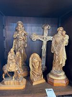 Photo showing five hand carved olive wood religious figures including Mary with baby Jesus, Joseph with child Jesus, a crucifix, a carved head bust, and Mary on a donkey figure.