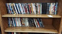 Two shelves of DVDs covering various genres, displayed on a wooden shelf