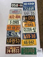 Photo showing vintage miniature bicycle license plates from various states and countries arranged on a white surface emphasizing the number and variety.