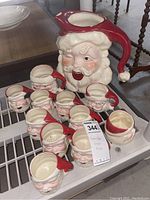 Wide view of pitcher and eleven mugs on metal shelf