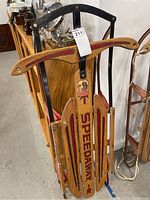 Full view of vintage Speedway sled showing wooden body, painted details and metal framework.