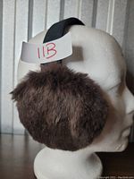 Side profile of the brown faux fur ear muffs on white mannequin head.