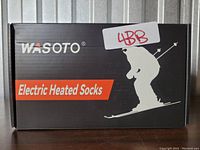 Front of the box shows the brand Wasoto and the product name Electric Heated Socks with a skier silhouette in white on black background.