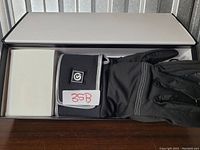 Photo of the gloves inside the box, black gloves with grey trim folded neatly.