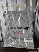 Gray Jed North apparel hoodie size XL in a sealed plastic packaging showing the logo and flag prints on the front.