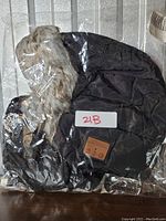 Black padded winter hat with faux fur trim and Bluetooth feature in clear plastic packaging.