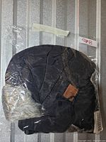 Black quilted winter hat with fur-lined ear flap in plastic packaging, showing Bluetooth functionality and a small brown leather detail.