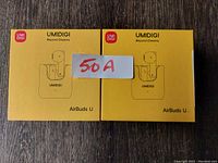 Two yellow boxed UMIDIGI AirBuds U wireless earbuds with red and white UMIDIGI branding and a sticker labeled '50 A' on one box.