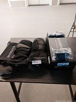 Full product photo showing Yowai heated mitts laid out next to original box and accessories such as charging cables.