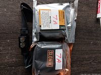 Photo of SLONIK headlamp with adjustable strap alongside two battery packs in branded black and silver sealed cases, all labeled with 7A sticker.