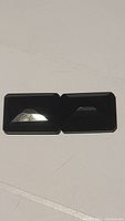 Pair of large, rectangular emerald cut black onyx gemstones placed side by side on a white surface showing their polished flat tops and faceted edges.