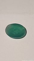 Top-down image of the green onyx showing the oval shape and transparent green color with checker cut facets.