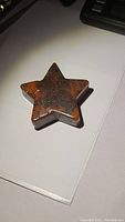 Top down image of hand carved red poppy jasper star showing its color and surface pattern.