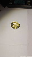 Photo showing top view of the oval cut lemon citrine gemstone on white background with weight scale in background.