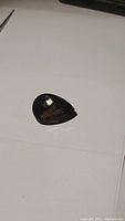 Pear-shaped dark brown smokey quartz gemstone showing checker cut facets on a white background.
