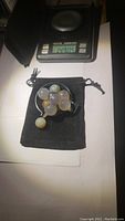 14 natural agate spheres on black pouch in front of a scale showing 164.95 carats total weight.