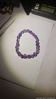 Natural purple amethyst stretchy bracelet laid flat on white surface, showing oval polished beads.