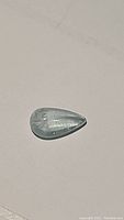 Pear-shaped aquamarine cabochon with soft blue color and visible inclusions on a neutral background.