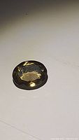 Oval cut natural champagne citrine gemstone on a plain white surface, showing high luster and facets