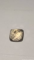 Photo of the single 12.2ct natural cushion cut citrine gemstone showing its light golden color and faceted cut.