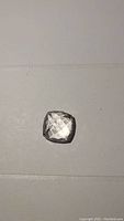 Single cushion cut clear transparent gemstone with polished facets, placed on a plain background for clear viewing.
