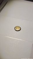 Photo of oval cut natural citrine gemstone on white background showing shape, color, and reflective qualities.