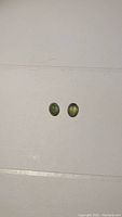 Two small oval green sapphires placed side by side on a flat surface.