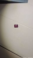 Overview of loose emerald cut ruby on white surface