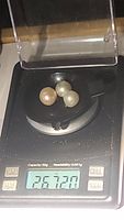 Three untreated pearls weighing a total of 26.72 carats on a digital scale.