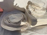Stack of various sizes and shapes of beige quilted fabric china protector bags, piled on top of each other showing zippered closures and quilted pattern.