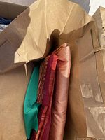 Top view inside a box showing fabric remnants stacked including green, rust, red checked, and peach colored pieces