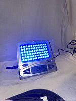 GoLite SAD light therapy lamp powered on showing blue LED lights and digital clock displaying 12:00