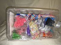 Plastic bin filled with assorted colorful elastic bands for crafting purposes.