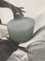 Stack of clear glass plates with textured lettuce leaf pattern visible on edges.